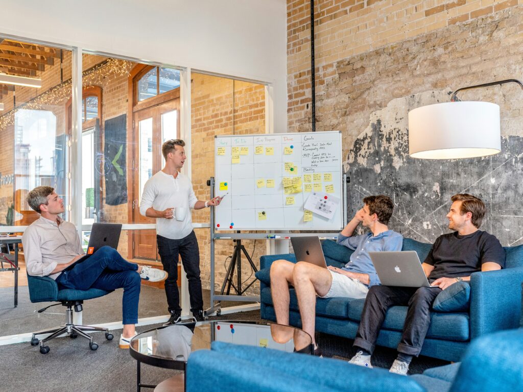 Group sitting around a whiteboard like a PMO startup.